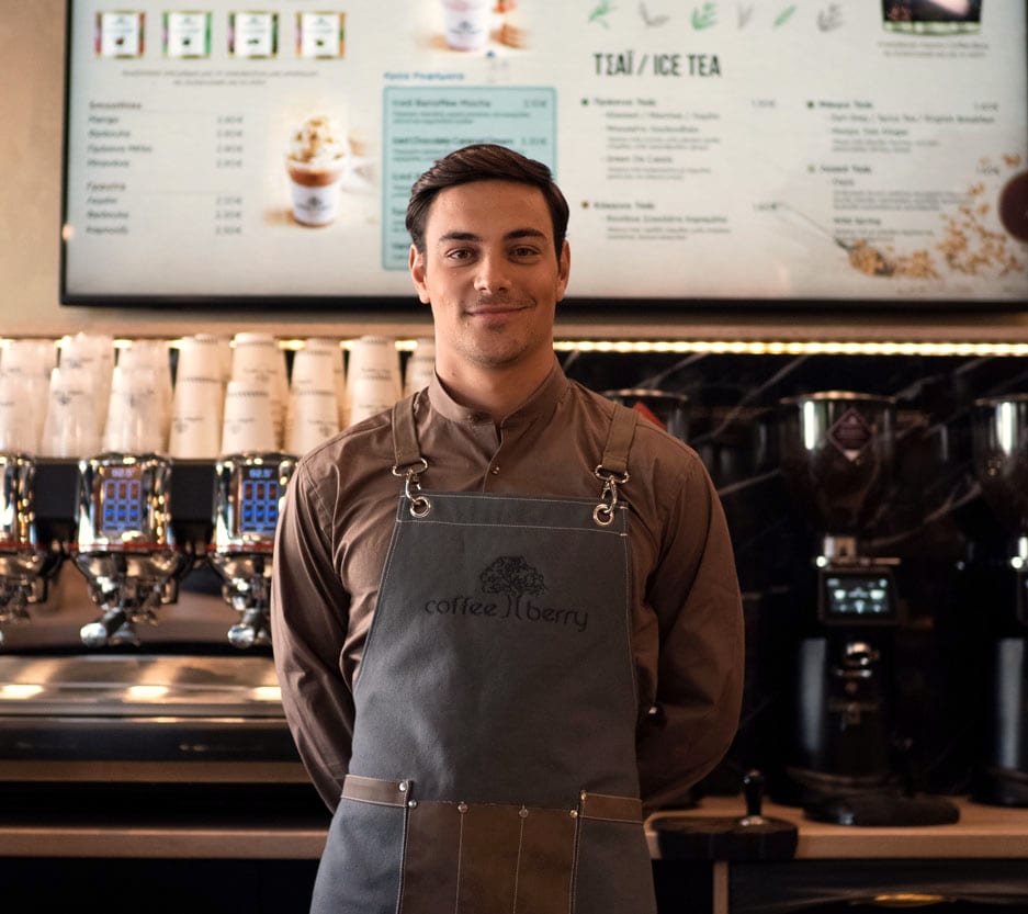 Barista της Coffee Berry στο κατάστημα, με χαμόγελο πίσω από τον πάγκο