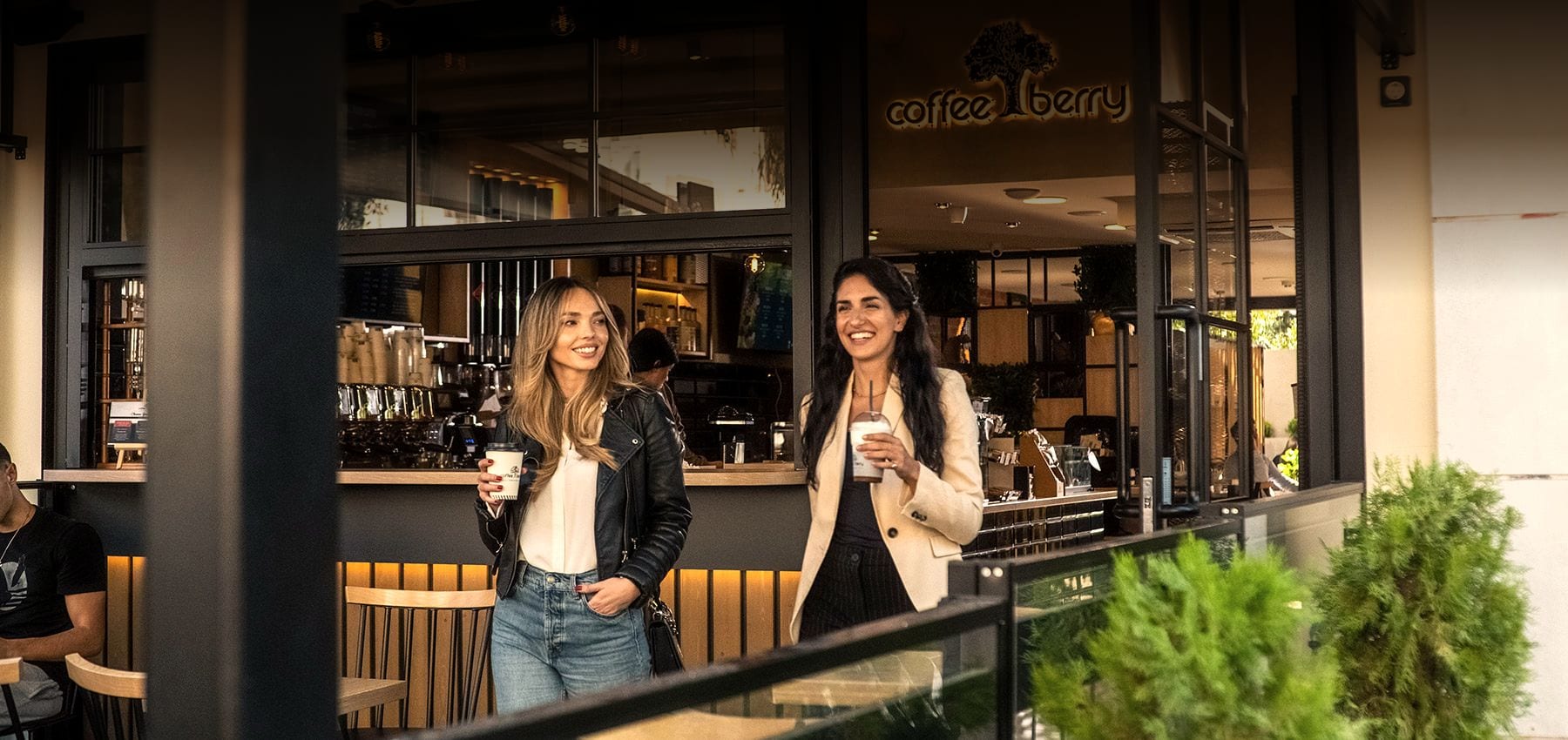 Δύο πελάτισσες βγαίνουν από κατάστημα Coffee Berry με καφέ στο χέρι